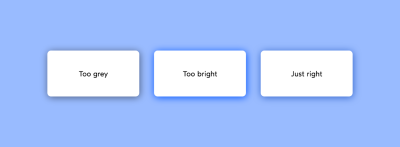 A screenshot of three white rectangles on a blue background, one with a grey shadow labeled 'Too grey', one with a bright blue shadow labeled 'Too bright', and one with a subtle blue shadow labeled ‘Just right’