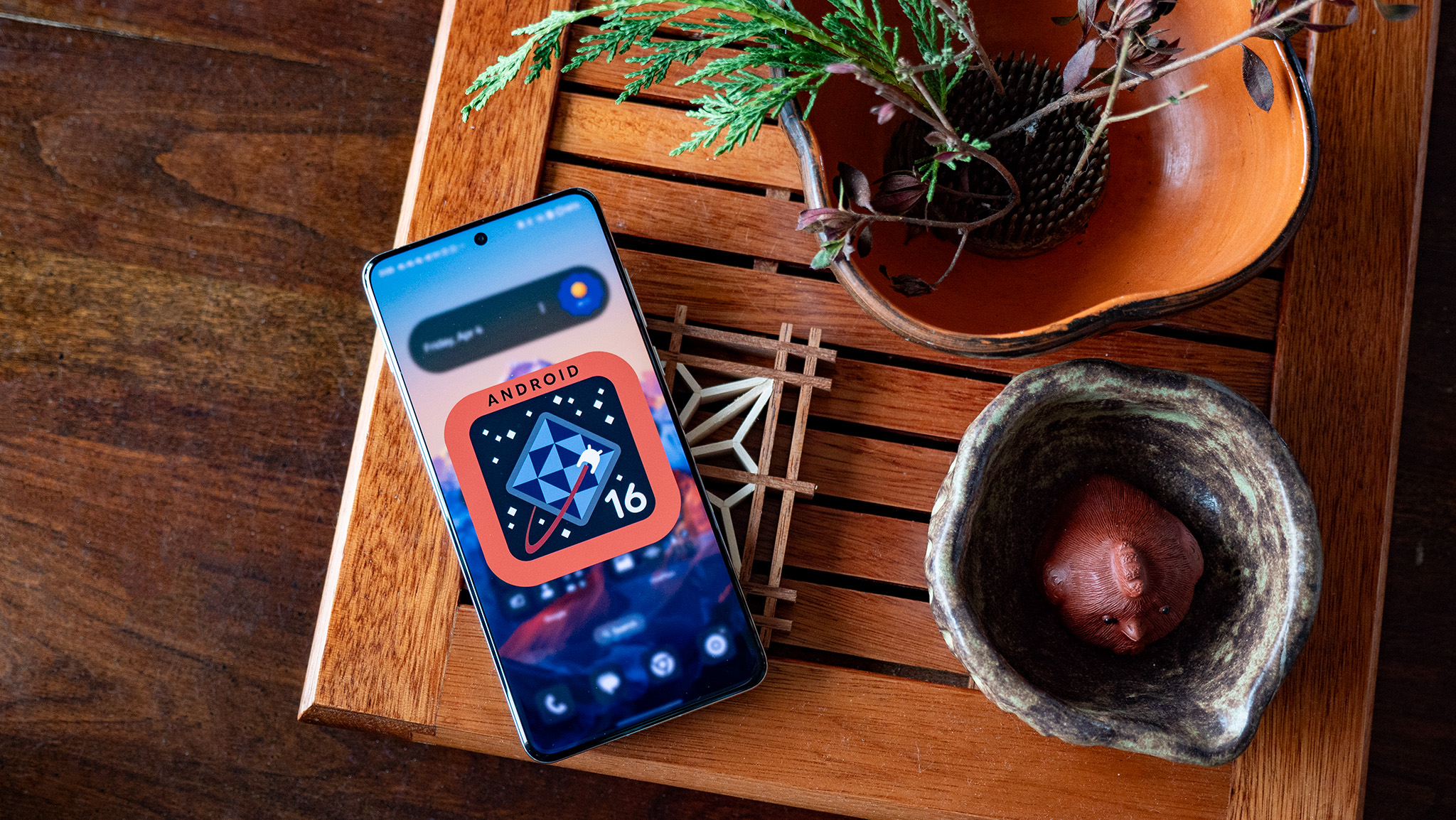 An orange and blue Android 16 logo on a OnePlus 13
