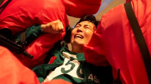 A man in a green-and-white tracksuit sobbing as he is handled by guards; Lee Jung-jae in 'Squid Game 3'