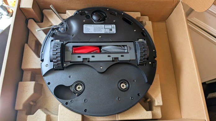 The underside of the Roborock Saros 10R robot vacuum, showcasing its cleaning technology and components inside a cardboard box.