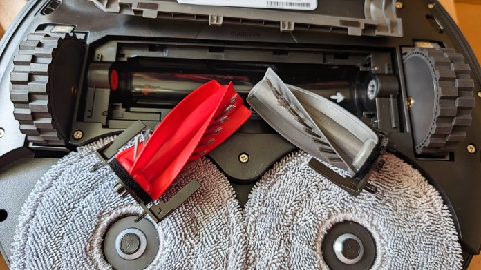 Close-up view of the underside of a Roborock Saros 10R robot vacuum, showcasing its dual anti-tangle brush system and mop pads.