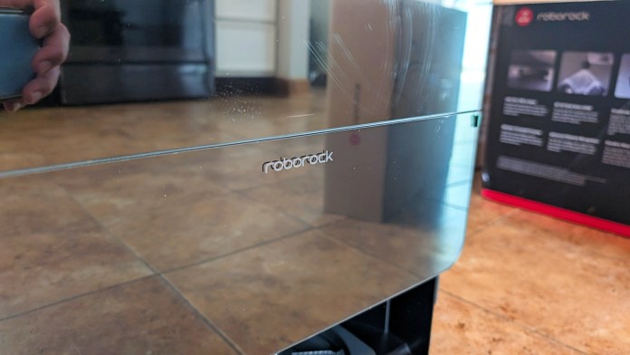 Close-up of the Roborock branding on a robot vacuum dock with a reflective glass surface.