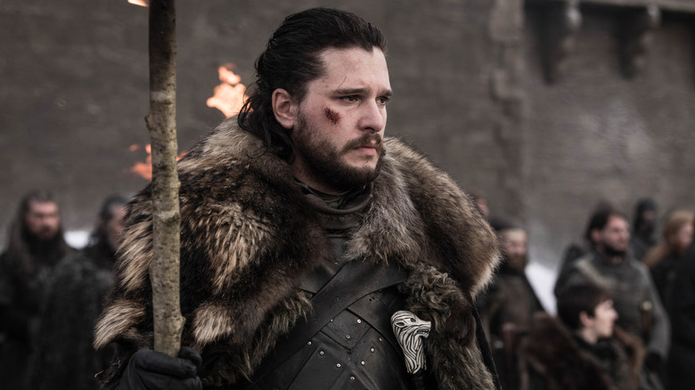 Jon Snow holding a torch with a cut on his cheek in Game of Thrones