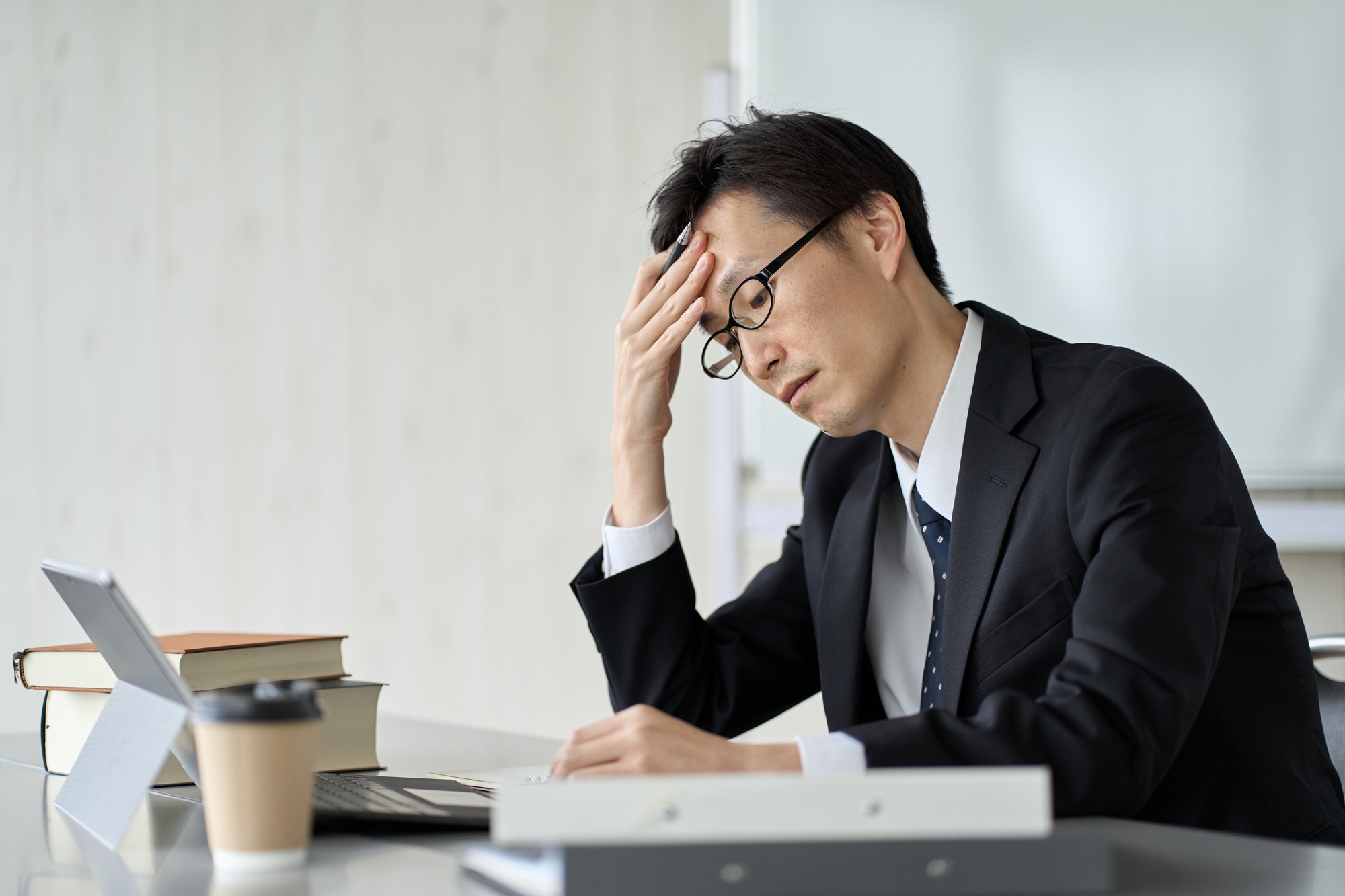 Worried asian businessman holding his head