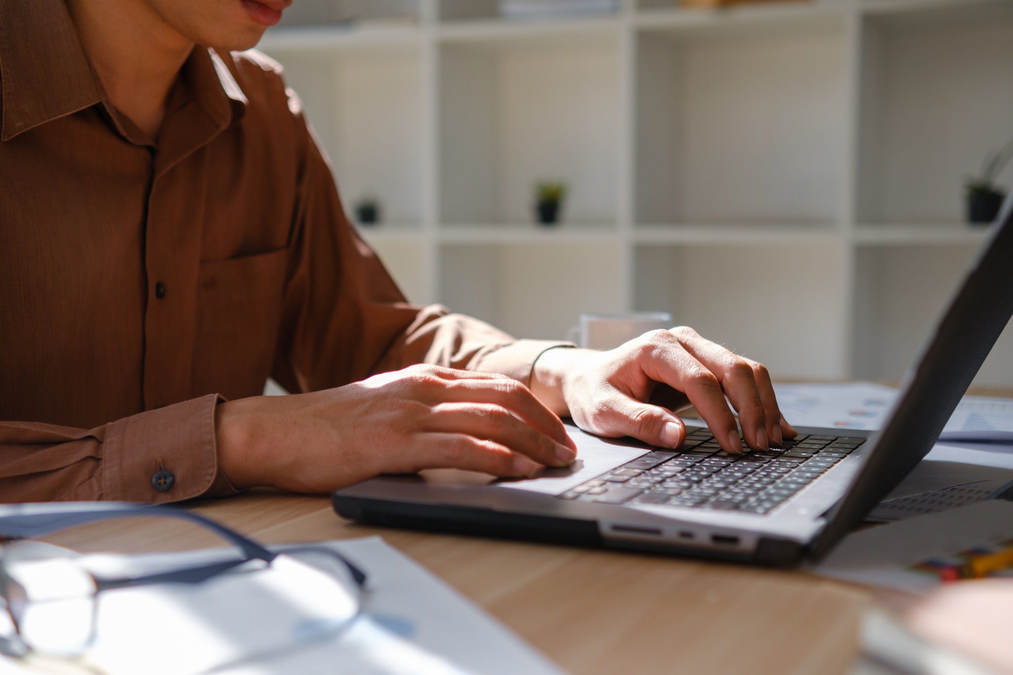 Close-up of hands typing on a laptop keyboard, working on business analysis and online learning.