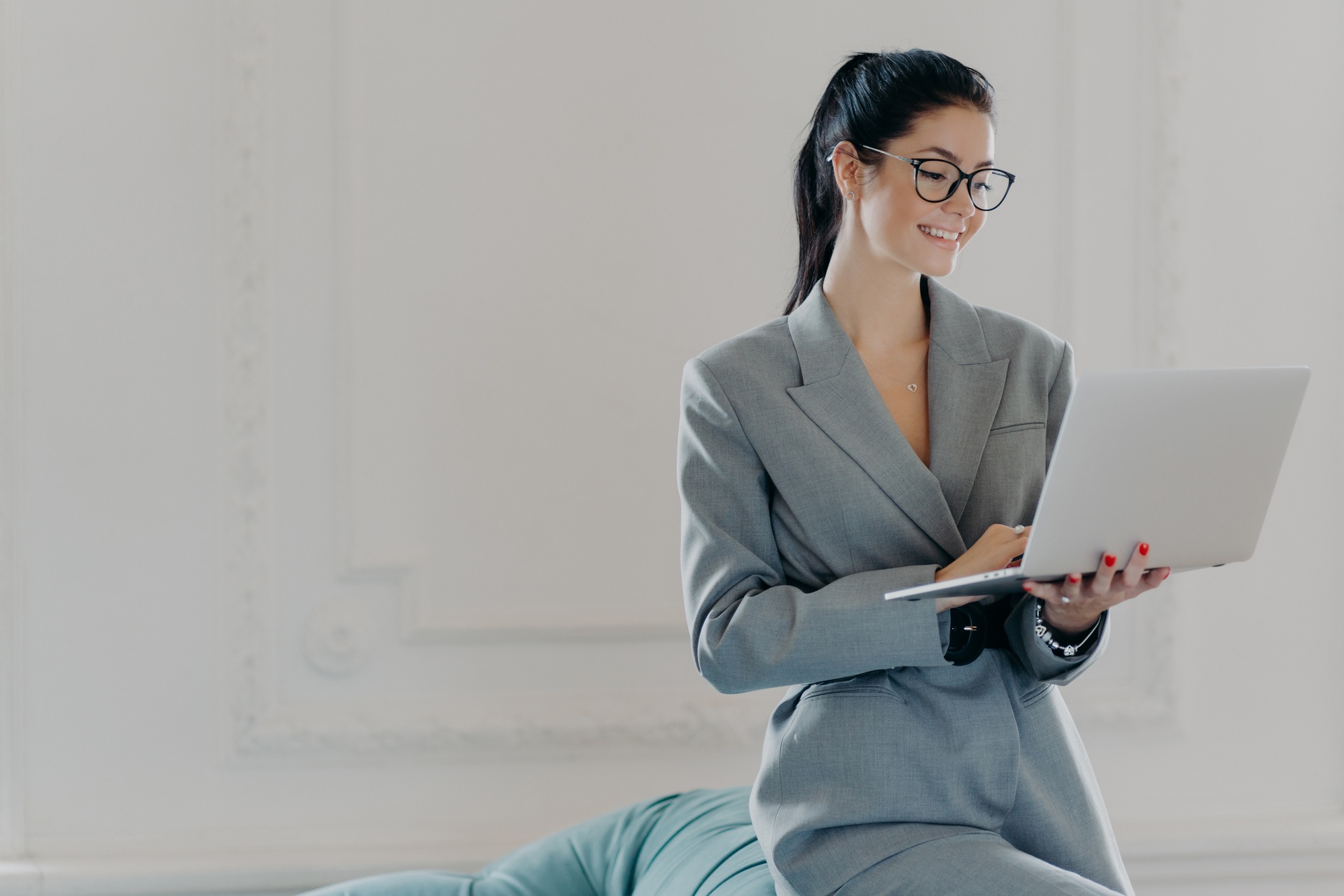 Happy female entrepreneur types on laptop computer, works in modern workspace in business center