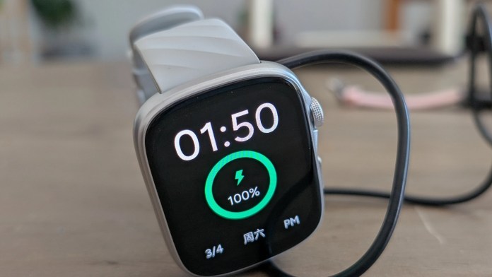Close-up of the Runmefit Watch 4 displaying the time and battery percentage while charging.