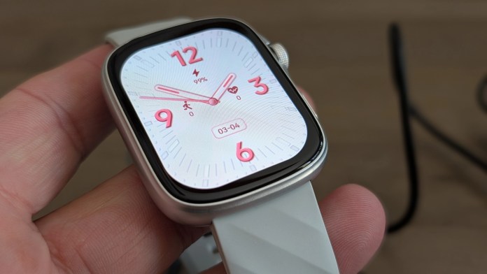 Close-up of a Runmefit Watch 4 smartwatch displaying a white watch face with red accents, showing time, battery percentage, and health metrics, held in a hand.