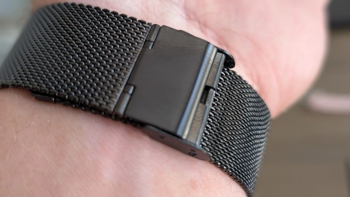 Close-up of a black mesh smartwatch band clasped around a wrist.