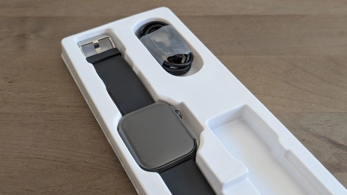 A Runmefit smartwatch placed in its packaging, featuring a sleek design with a black strap and a square display.