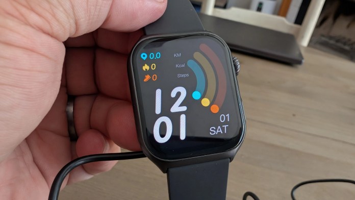 Close-up of a smartwatch screen displaying the date, time, and fitness metrics such as distance, calories burned, and steps taken, held in a hand.