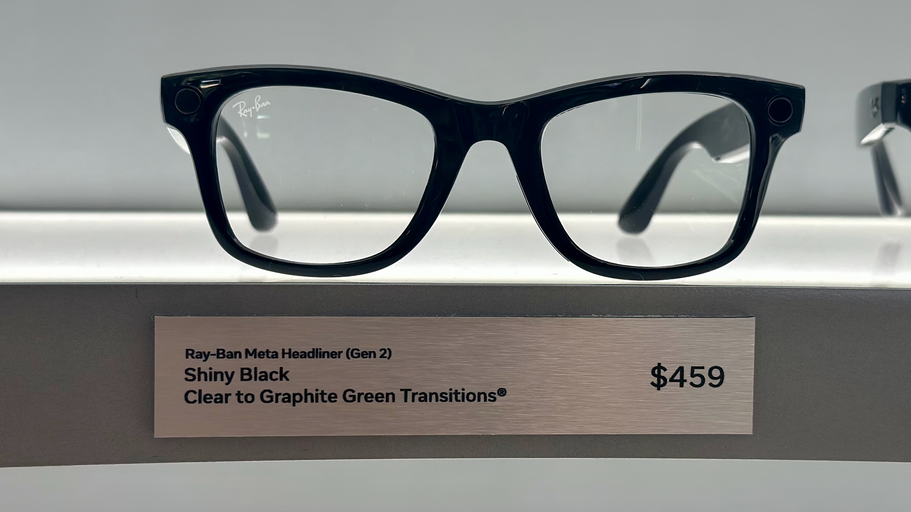 Headliner Ray-Ban Meta (Gen 2) glasses on display in Shiny Black with Clear to Graphite Green Transitions lenses.