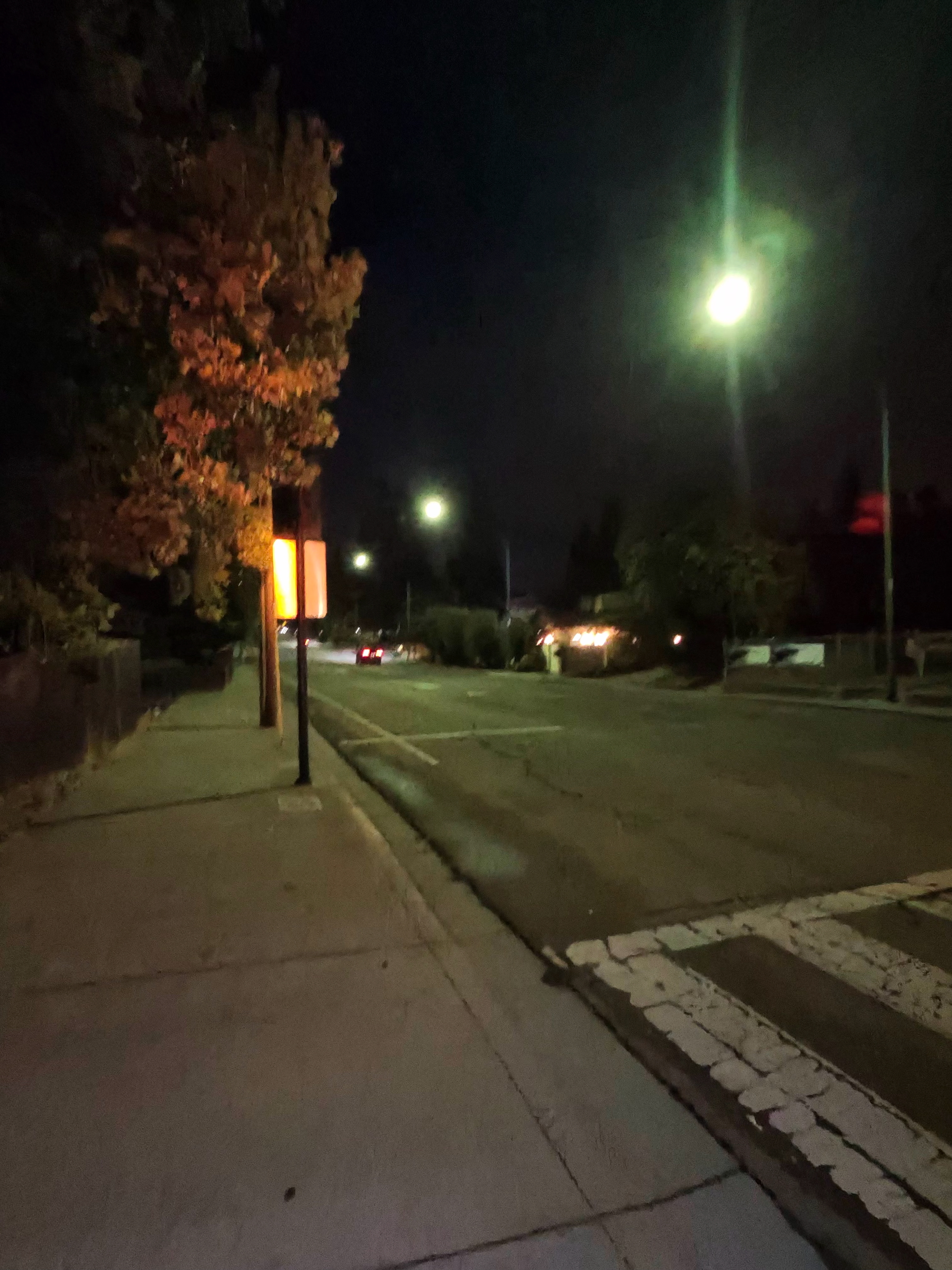 A photo taken with the Ray-Ban Meta (Gen 2) smart glasses showing a dark street with street lamps illuminating it at night.