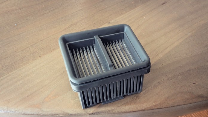 A close-up view of a wet/dry vacuum filter, showcasing its layered design and textured sides, placed on a wooden surface.