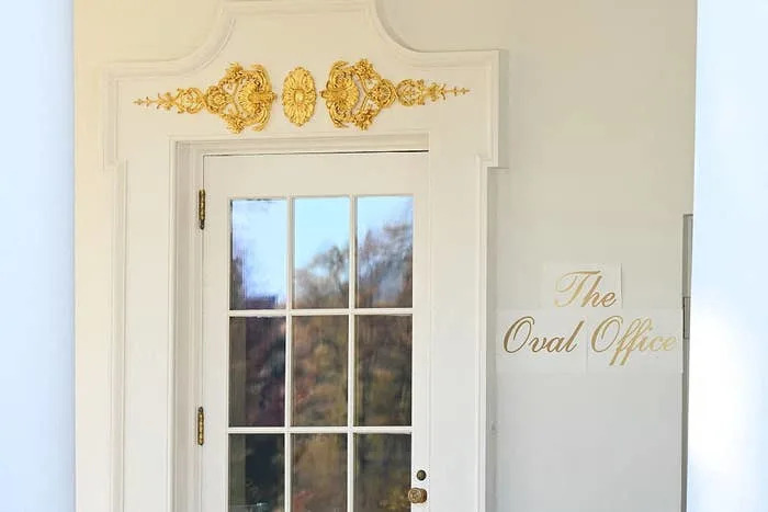 Elegant door with ornate gold details and a sign reading "The Oval Office" beside it